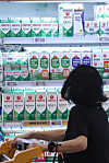 A customer looks at different milk brands displayed at a supermarket in Seoul on Wednesday. [YONHAP]