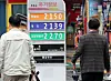People walk past a sign board showing oil prices in Seoul on Tuesday. The Ministry of Economy and Finance announced Tuesday it would extend tax cuts on fuel for four months through August. [NEWS1]