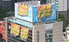Three truck drivers in the Cargo Truckers Solidarity sit on top of a billboard installed at HiteJinro’s headquarters in Gangnam District, southern Seoul. Around 100 unionized workers occupied the building lobby and rooftop on Tuesday. [YONHAP]