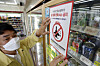 An official puts a sticker on a refrigerator door saying that alcohol and tobacco sales to people under the age of 19 are prohibited at a convenience store in Buk District, northern Gwangju, on Tuesday. Korea adopted the international method of counting age starting Wednesday, however, the legal age to drink and smoke are unaffected by the change. [BUK DISTRICT]