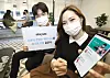 Models hold up a mobile phone with the app for Blice on Tuesday, prior to the press conference held at Gwanghwamun, central Seoul. Blice is a web novel platform run by Storywiz. [KT]