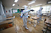 Sanitization workers disinfect a high school classroom in Daegu on Sunday afternoon ahead of the school reopening. [YONHAP]