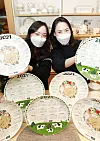 Models pose with dishes showing the 2021 calendar and images of white oxen, made by ceramic company ZEN, at Lotte Department Store’s headquarters in central Seoul on Monday. According to the lunar calendar, 2021 is the year of the white ox, signifying peace and leisure. [YONHAP]