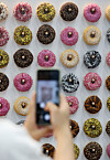 A visitor takes a photo of various types of donuts displayed at the 2022 Suwon Cafe & Bakery Fair on Thursday, held at the Suwon Convention Center in Gyeonggi. [NEWS1]