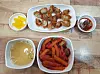 A tteokbokki-sundae-fries combo, bottom right, and mini fried dumplings, top center, served with fish cake soup, bottom left, pickled raddish, top left, and soy sauce on the side at Gamdong Twikim.[PAIK JI-HWAN]