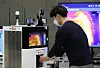 An employee disinfects his hand using an autonomous disinfectant robot deployed at SK Telecom’s headquarters in Euljiro, Jung District, in central Seoul on Tuesday. SK Telecom announced Tuesday that it has co-developed the robot with industrial automation solution provider Omron that can monitor and send visitor data via the 5G network to a central server. [YONHAP]