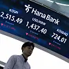 A broker stands under a screen showing market close at a Hana Bank trading room in Seoul on Jan. 23. [YONHAP]
