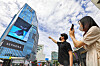 Passersby take photos of a media art piece showcased via a digital sign on an outer wall of the Hyundai U-Plex Department Store in Sinchon, western Seoul, on Wednesday morning. [YONHAP]