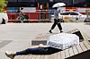 A person covers their face and upper torso with a sun shade while lying on a bench in central Seoul on Wednesday. [YONHAP]