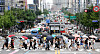 Pedestrians at a crosswalk in the Hongdae area in Mapo District, western Seoul, protect themselves from the rain on Saturday as the rainy season started. [YONHAP]
