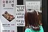 A passerby checks the price of gimbap (seaweed rice rolls) outside a restaurant in Gwancheol-dong in Jongno District, central Seoul on Thursday afternoon. [YONHAP]
