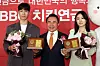 Short-track speed skating gold medalists Hwang Dae-heon, left, and Choi Min-jeong, right, pose for a photo after receiving a plaque from Genesis BBQ chairman Yoon Hong-geun at the Lotte Hotel Seoul on Thursday. Genesis BBQ, the operator of fried chicken chain BB.Q Chicken, will provide Olympic gold medalists with membership reward points worth 30,000 won ($24) every day until they turn 60. [NEWS1]