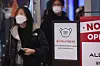 Visitors to a mall in Seoul walk past a sign on Thursday that reminds the public to wear their masks. [YONHAP]