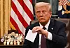 U.S. President Donald Trump holds up outgoing President Joe Biden's letter as he signs executive orders in the Oval Office of the White House in Washington on Jan. 20. [AFP/YONHAP]