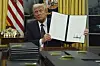 U.S. President Donald Trump holds up an executive order commuting sentences for people convicted of Jan. 6 offenses in the Oval Office of the White House in Washington, Jan. 20, [AP/YONHAP]