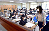 A teacher measures body temperatures of students before they take a trial college entrance examination in Dunwon High School in Daejeon on Wednesday. Around 480,000 students across the country applied for the mock exam, 11.3 percent less than the number last year.  [KIM SEONG-TAE]