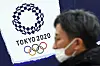 A man wears a protective mask to help curb the spread of the coronavirus near the logo of the Tokyo 2020 Olympic Games. [AP/YONHAP]