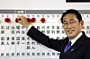 Japan's prime minister and ruling Liberal Democratic Party leader Fumio Kishida puts rosettes above the names of successful general election candidates on a board at the party headquarters in Tokyo on Oct. 31. [BEHROUZ MEHRI/AP/YONHAP]