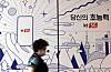 A citizen walks past a phone shop in central Seoul on Wednesday. [YONAHP]