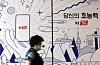 A citizen walks past a phone shop in central Seoul on Wednesday. [YONAHP]