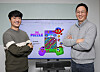 Na Young-chae, left, and Lee Chin-ho, co-CEOs and founders of Supergene, stand before a screen featuring Supergene's social game 'The Puzzle' at its office in Pangyo, Gyeonggi. [PARK SANG-MOON]