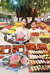 A lady holds a dish of tuna sashimi and a girl holds a plate filled with chicken gangjeong which is a fried chicken marinated in a spicy and sweet sauce at E-mart’s Yongsan branch in central Seoul. Starting from Thursday, the retailer will offer delicacies and fruits for family gatherings during the Lunar New Year holiday at discounted prices. [YONHAP]