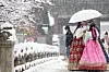 People wearing hanbok (traditional Korean dress) chat as they view the snow-covered Gyeongbok Palace in central Seoul on Wednesday. [YONHAP]