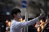 Jin appears to be taking a selfie as he waits for the Olympic torch to be passed on July 14. [AP/YONHAP]
