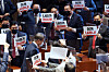 As President Moon Jae-in leaves the main hall of the National Assembly after delivering the 2021 budget speech, lawmakers of the opposition People Power Party show him protesting signs, asking 'What happened to this country?' on Wednesday. [YONHAP]