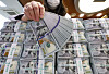 A banker checks dollar bills at Hana Bank's Counterfeit Notes Response Center in Seoul on March 31. [YONHAP]