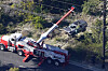 Workers move a vehicle after a rollover accident involving golfer Tiger Woods on Tuesday in Rancho Palos Verdes, Calif., a suburb of Los Angeles.. Woods suffered leg injuries in the one-car accident and was undergoing surgery, authorities and his manager said. [AP]