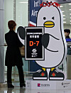 Busan's feathered mascot Boogi holds up a sign indicating that there are seven days left until the vote for the hosting city of the World Expo 2030, at Gimhae International Airport in South Gyeongsang on Tuesday. Korean politicians and businessmen alike are making final efforts in support of Busan's bid for the expo ahead of the final vote scheduled for Tuesday in Paris. [YONHAP]