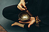 A person plays a singing bowl, an instrument used during a sound bath session that facilitates meditation. [SHUTTERSTOCK]