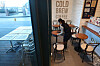 A worker at a coffee shop in downtown Seoul wipes tables Sunday, a day before customers will be allowed to eat and drink at cafes in Seoul, Incheon and Gyeonggi. [YONHAP]