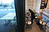 A worker at a coffee shop in downtown Seoul wipes tables Sunday, a day before customers will be allowed to eat and drink at cafes in Seoul, Incheon and Gyeonggi. [YONHAP]