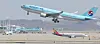A Korean Air plane takes off at Incheon International Airport with an Asiana Airlines plane taxing behind. [YONHAP]