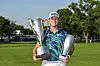 Viktor Hovland of Norway smiles with the Western Golf Association trophy, left, and the BMW Championship trophy after his victory in the final round of the BMW Championship, the second event of the FedExCup Playoffs, on the North Course at Olympia Fields Country Club in Olympia Fields, Illinois on Sunday. [GETTY IMAGES]