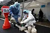 Medical workers deploy sand bags at tents for Covid-19 testing in Gwangju on Monday as winds picked up as Typhoon Omais approached the Korean Peninsula. [YONHAP]