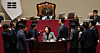 Lawmakers from rival parties crowd around the podium and raise their voices as Rep. Na Kyung-won of the People Power Party, center front, stages a filibuster against proposed amendments to the Fair Transactions in Franchise Business Act during a plenary session at the National Assembly on Dec. 9. [YONHAP]
