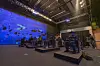 Audience members wear virtual reality (VR) headsets and hand controllers to enjoy the show. Computers are installed underneath each seat to allow this live digital VR performance to be possible. [ACC]