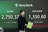 A currency trader moves by the screens showing the Kospi, left, and the foreign exchange rate between U.S. dollar and Korean won in the foreign exchange dealing room of the KEB Hana Bank headquarters in Seoul, Korea, Thursday. [AP/ YONHAP]