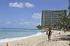 In this June 5, 2020, file photo, a surfer walks on a sparsely populated Waikiki Beach in Honolulu. Hawaii's governor says that starting Oct. 15, travelers arriving from out of state may bypass a 14-day quarantine requirement if they test negative for Covid-19. [AP/YONHAP]