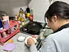 Koo Hye-bin, an 11-year-old family caregiver, prepares to cook eggs with her left hand as her right hand was injured to a recent fall last Thursday. [LEE BO-RAM]