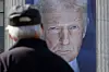A pedestrian passes by a banner showing an image of U.S. President Donald Trump hangs on the side of a U.S. Department of Agriculture building in Washington on May 16. [AFP/YONHAP]