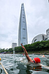 Participants swim across Seokchon Lake in Jamshil, Songpa District, southern Seoul, on the morning of July 6 during the 2025 Lotte Aquathlon.[NEWS1]