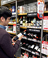 A customer examines a bottle of wine displayed at an Emart24 convenience store. [YONHAP]