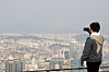 A man takes a photo of downtown Seoul from a trail on Mount Namsan on Tuesday as fine dust partially obscures the view. [JANG JIN-YOUNG]