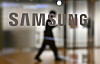 A man walks past the Samsung logo displayed on a glass door at the company's Seocho building in Seoul. [AFP]