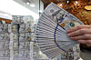 An employee holds stacks of dollar bills at Hana Bank's Counterfeit Notes Response Center in Jung District, central Seoul on Wednesday. Korea's foreign exchange reserves fell to $449.3 billion in April, down by $8.5 billion on month, according to the Bank of Korea Wednesday. The central bank cited the strong dollar and measures to ease volatility in the foreign exchange market as the reasons behind the drop. [NEWS1]
