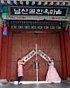 Visitors pose in front of the entrance of the Namsangol Hanok Village in Jung District, central Seoul. [JOONGANG ILBO]